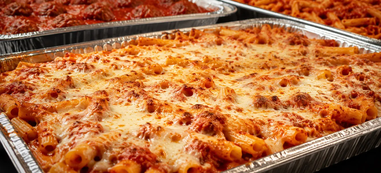 Catering trays of baked ziti with melted mozzarella and meatballs