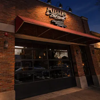 Millie’s Old World storefront at dusk, with its red awning and illuminated sign