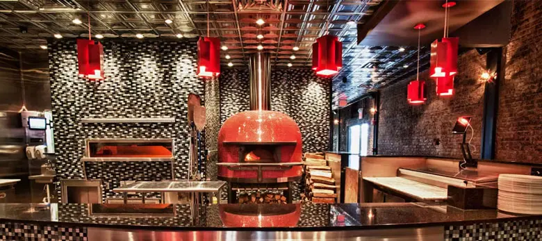 Millie’s open kitchen with its red-tiled wood-fired pizza oven beneath red pendant lights