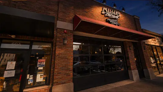 Millie’s Old World storefront on South Street at dusk, with its red awning and illuminated sign