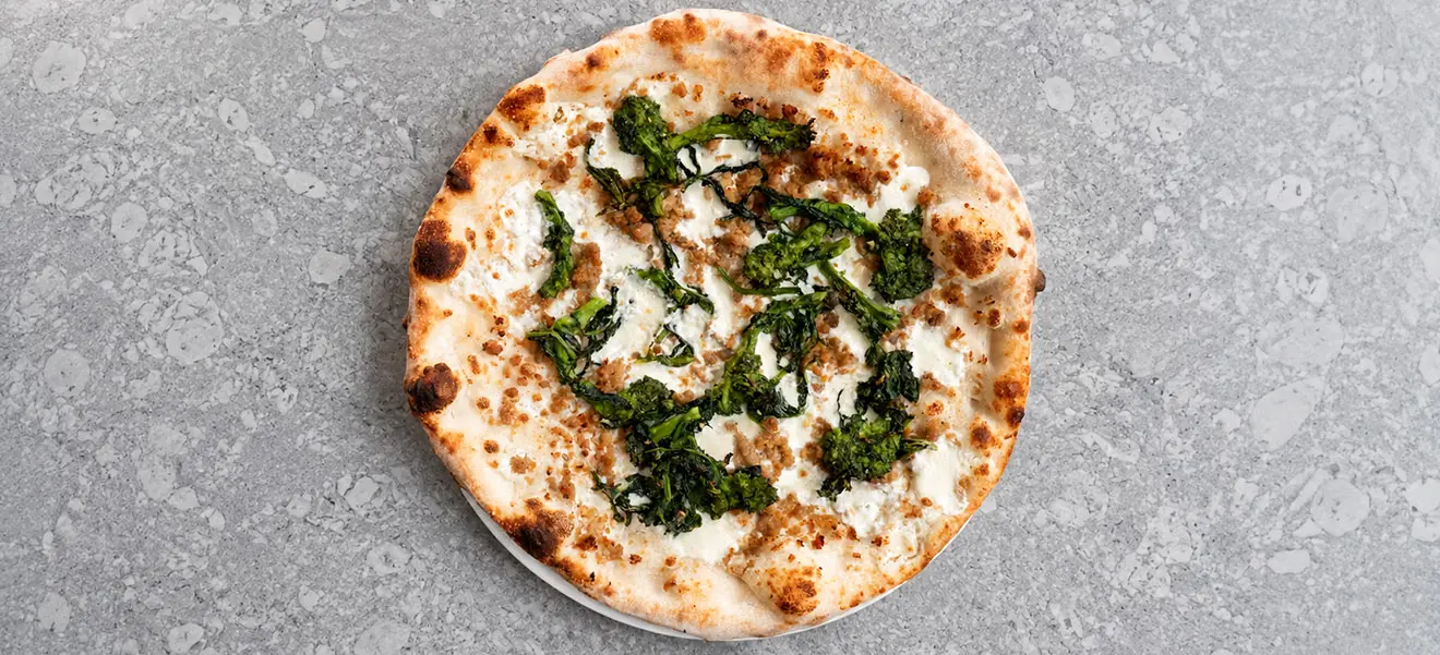 A white pizza topped with broccoli rabe and sausage