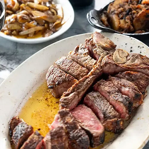 A sliced porterhouse steak with sautéed onions and mushrooms