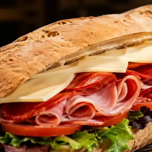 An Italian sub with ham, salami, provolone, lettuce and tomato