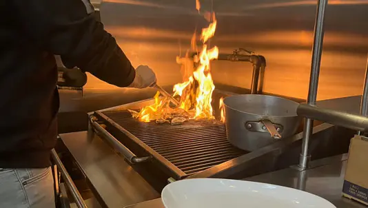 Steaks searing over open flames on the kitchen grill