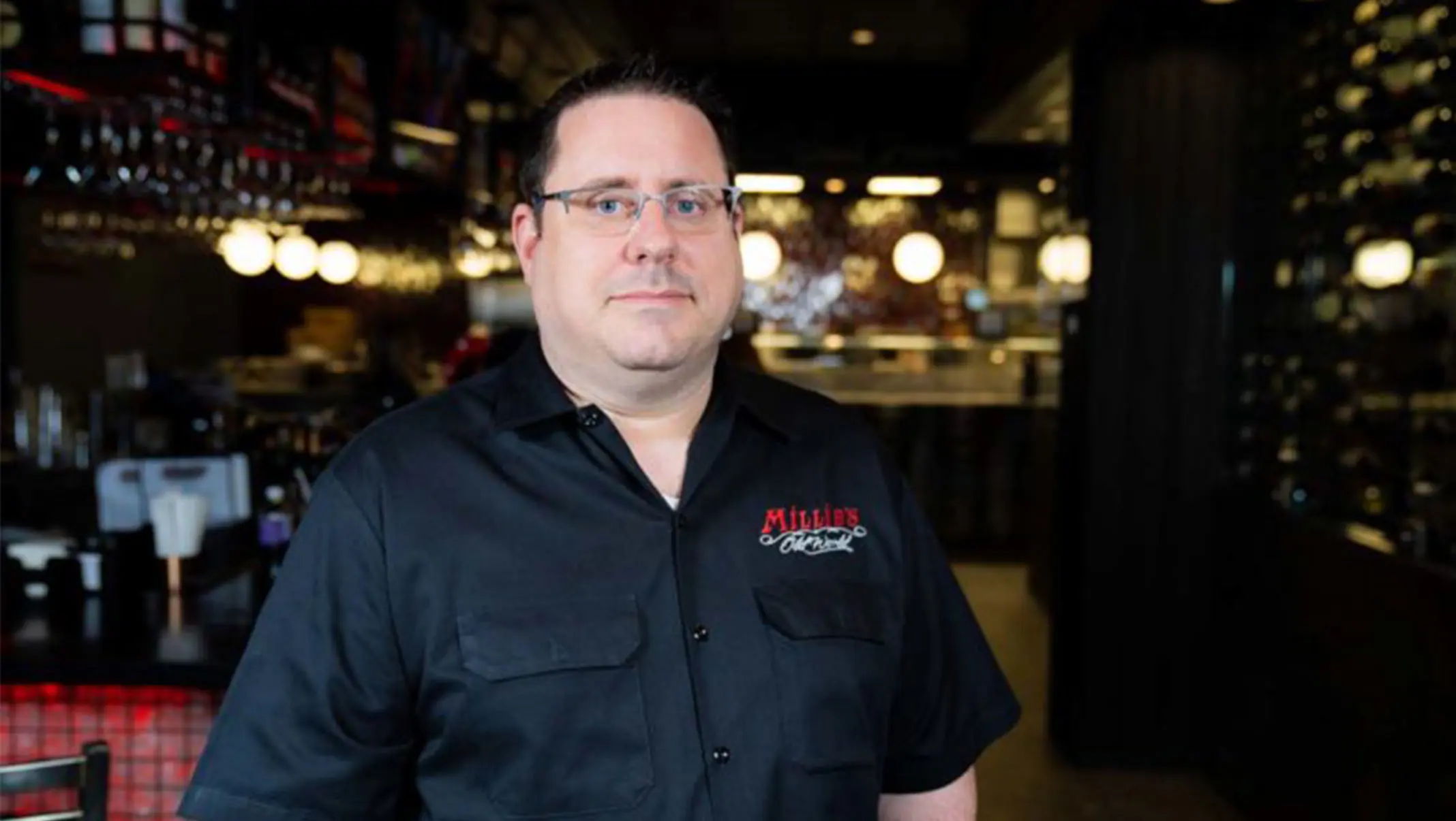 Man in a Millie’s shirt standing in the restaurant’s dining room