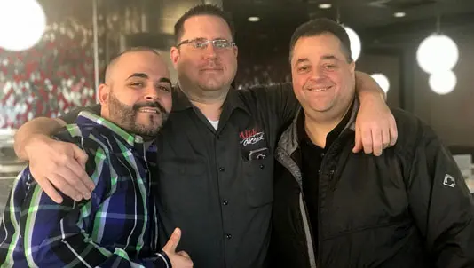 Three men smiling together inside the restaurant