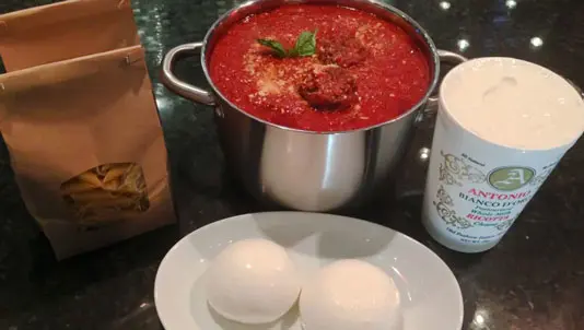 Pot of meatballs in sauce with bread and fresh mozzarella